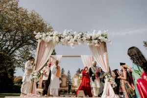 Wedding guests gathered under floral arch for outdoor ceremony celebration.