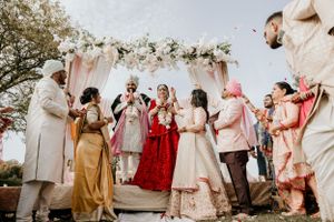 Festive Indian wedding celebration with guests gathered under a decorated floral mandap.