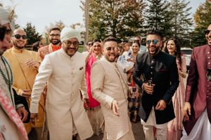 Outdoor gathering with guests wearing traditional Indian formal wear in autumn setting.