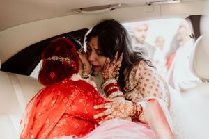A tender moment shared in the backseat of a car adorned in traditional South Asian wedding attire.