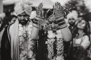 Close-up of decorated hands with intricate mehndi designs shown in black and white photography.