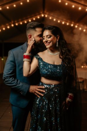 Romantic couple in formal attire share an intimate moment under twinkling lights.