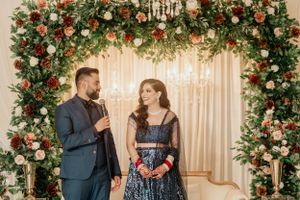 Couple sharing conversation under beautifully decorated floral arch at wedding reception.