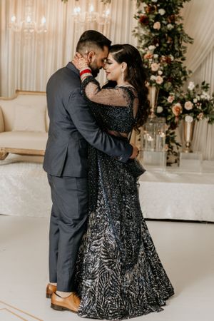 Romantic moment captured under an ornate floral arch at an elegant wedding reception.
