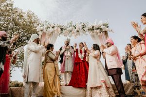 Joyous wedding celebration with guests gathered around decorated mandap outdoors.