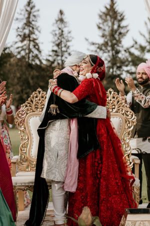 Intimate moment during an Indian wedding ceremony with couple embracing on ornate golden throne.