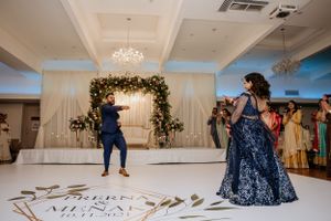 Couple dancing at their wedding reception under an elegant floral arch and chandelier.