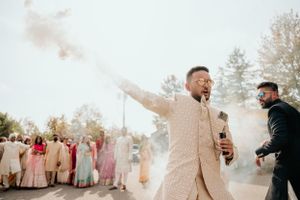 Joyous celebration at Indian wedding with smoke effects and dancing.