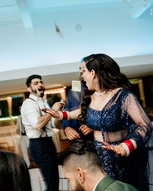 A lively celebration moment at an Indian wedding reception showing dancing and joyful interactions.