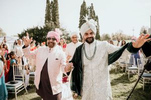 Wedding celebration in garden setting with guests in traditional attire and decorative chairs.