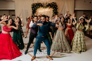 Wedding guests dancing in vibrant traditional outfits during reception celebration.
