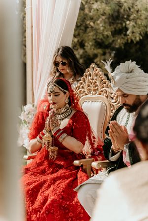 Intimate moment during traditional South Asian wedding ceremony under draped canopy.