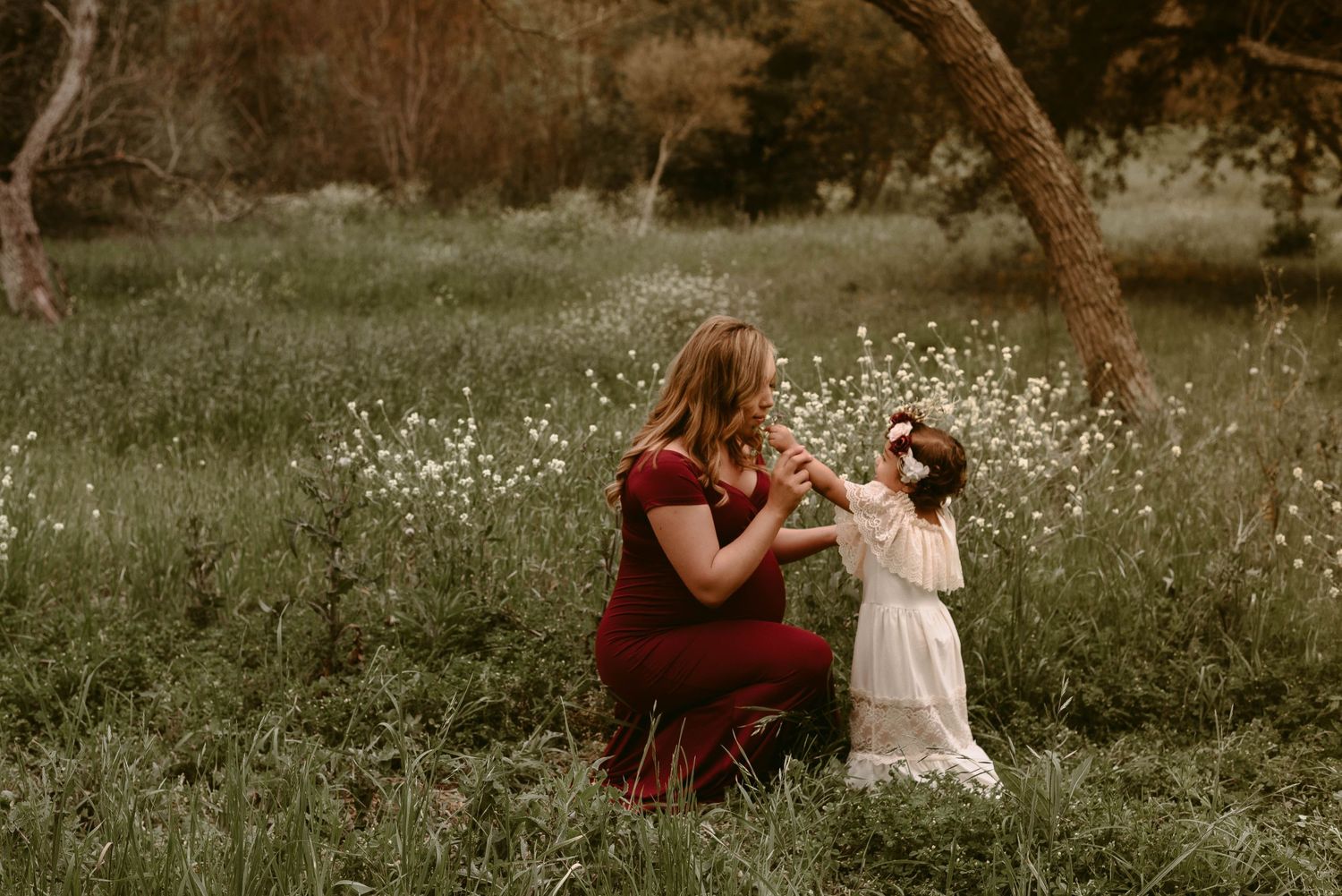 Tender moment between mother and child sitting in a wildflower field.