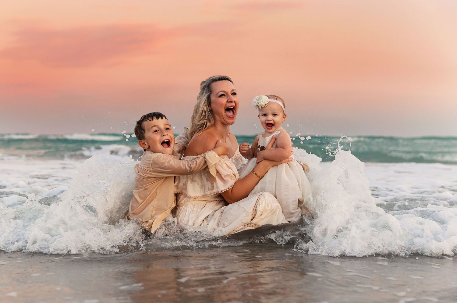 Joyful family moment captured in ocean waves at sunset.