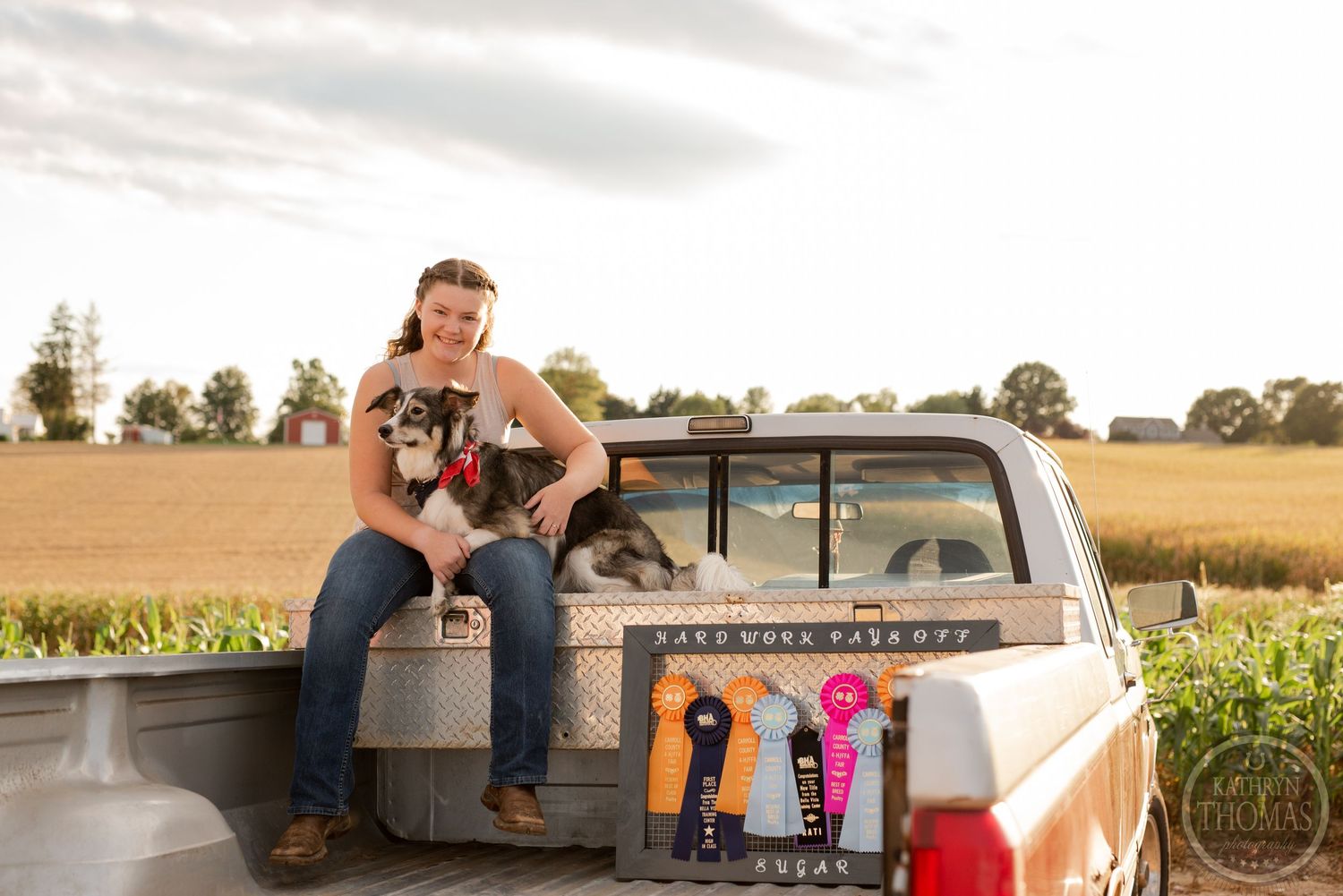 Sun-lit portrait taken in the bed of a vintage pickup truck with corn fields in background.