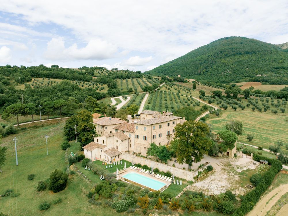 Scenic aerial view of Borgo Colognola with a sparkling pool nestled amidst lush surroundings