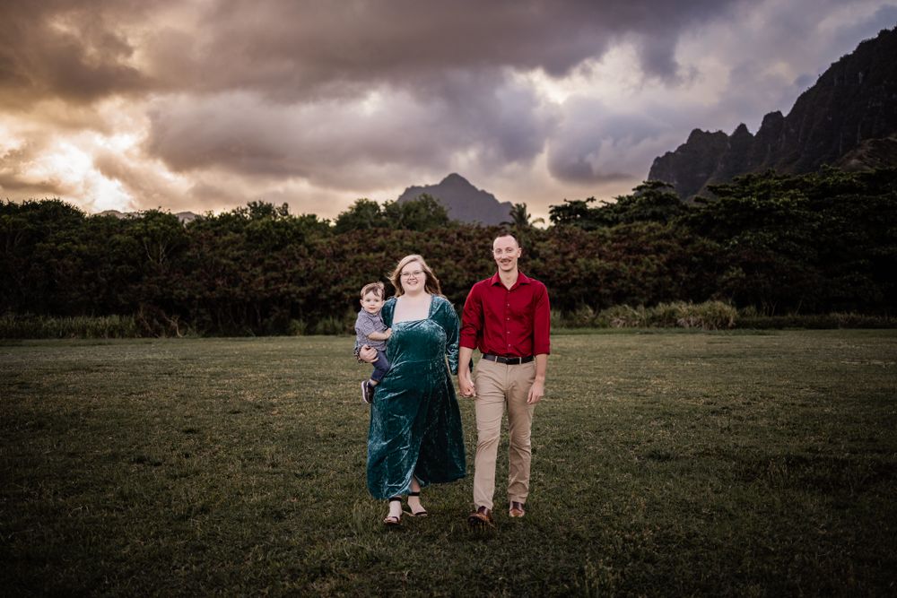 Family portrait with dramatic mountain backdrop and stormy sunset sky.