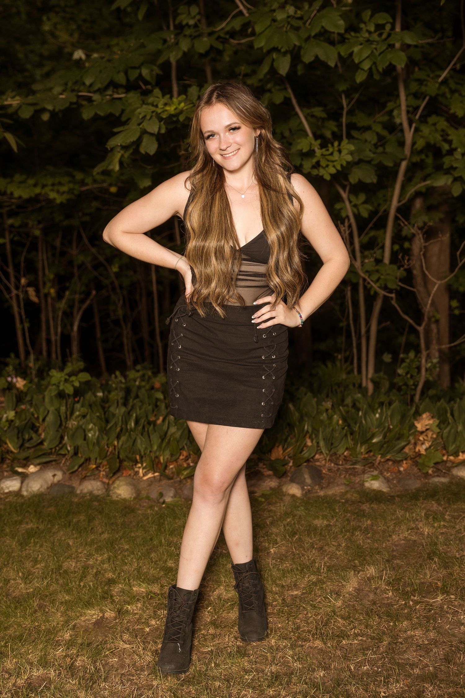 Person in fitted black dress poses confidently on autumn evening outdoors.