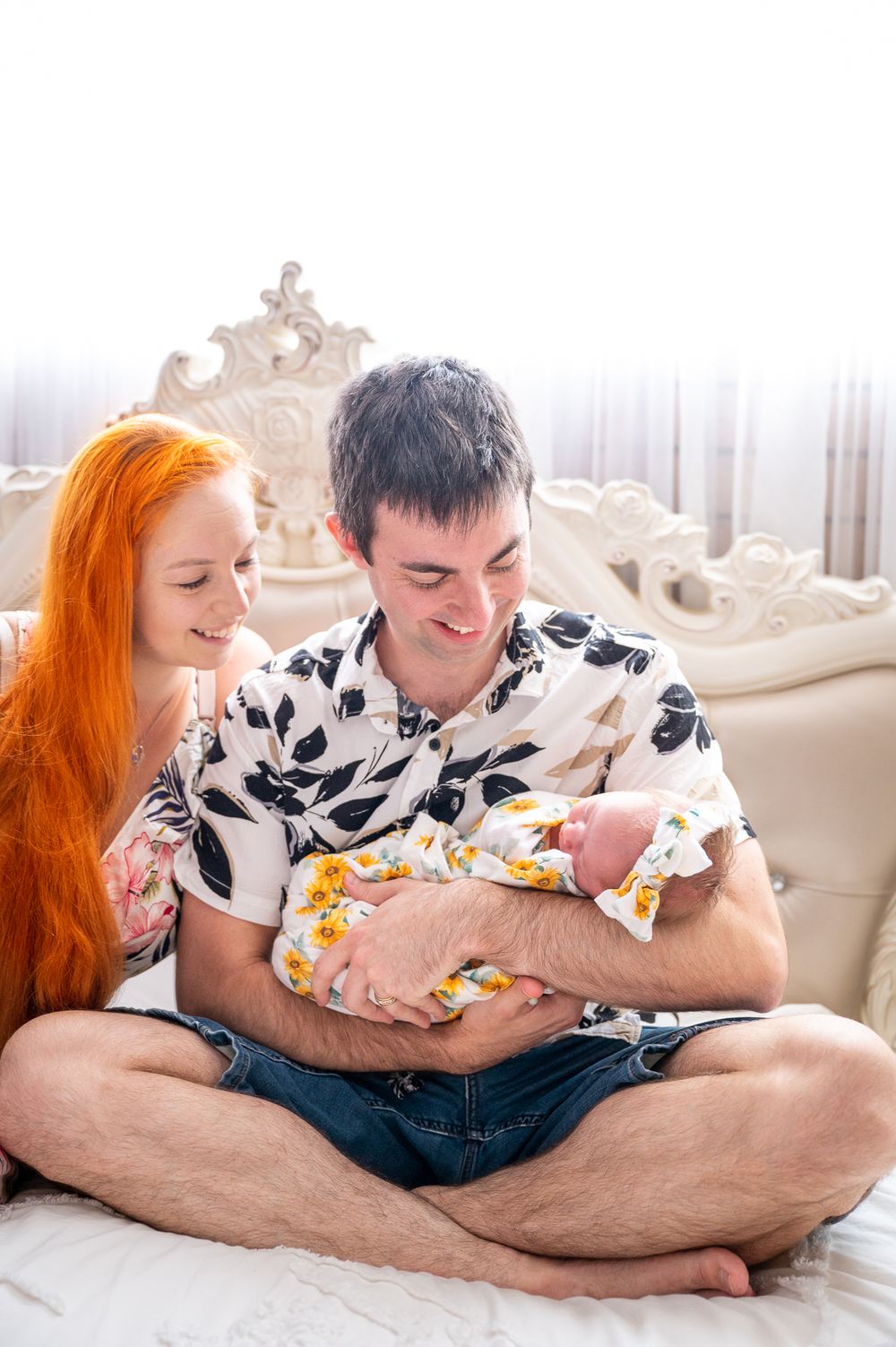 Newborn being held in dad's arm as Mum looks on.