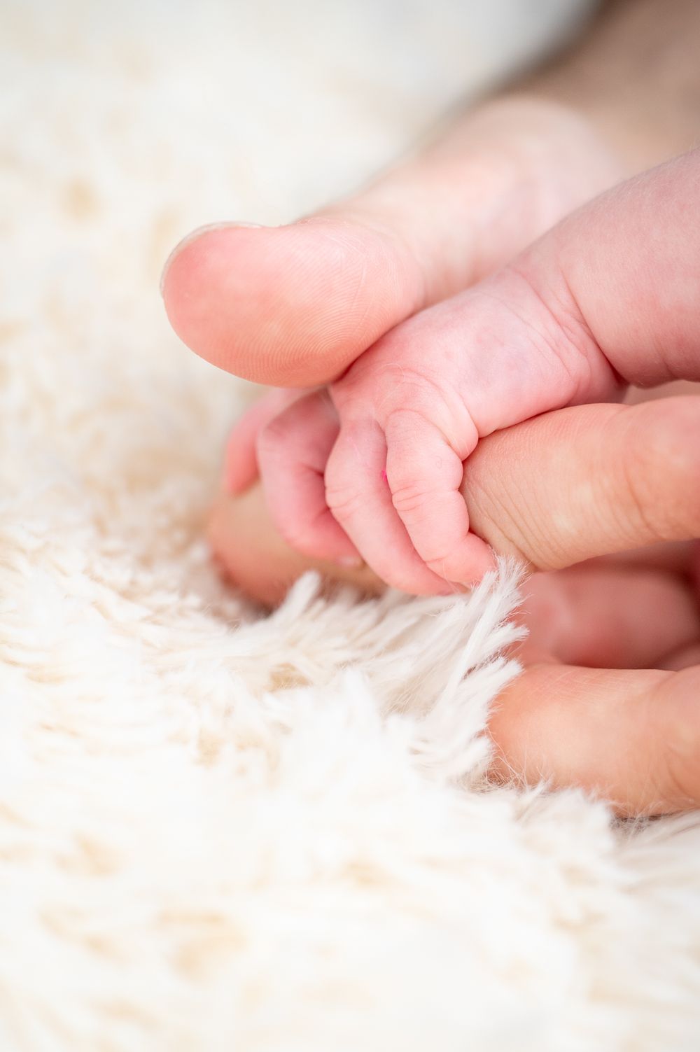 Newborn hand wrapped around her daddy's finger