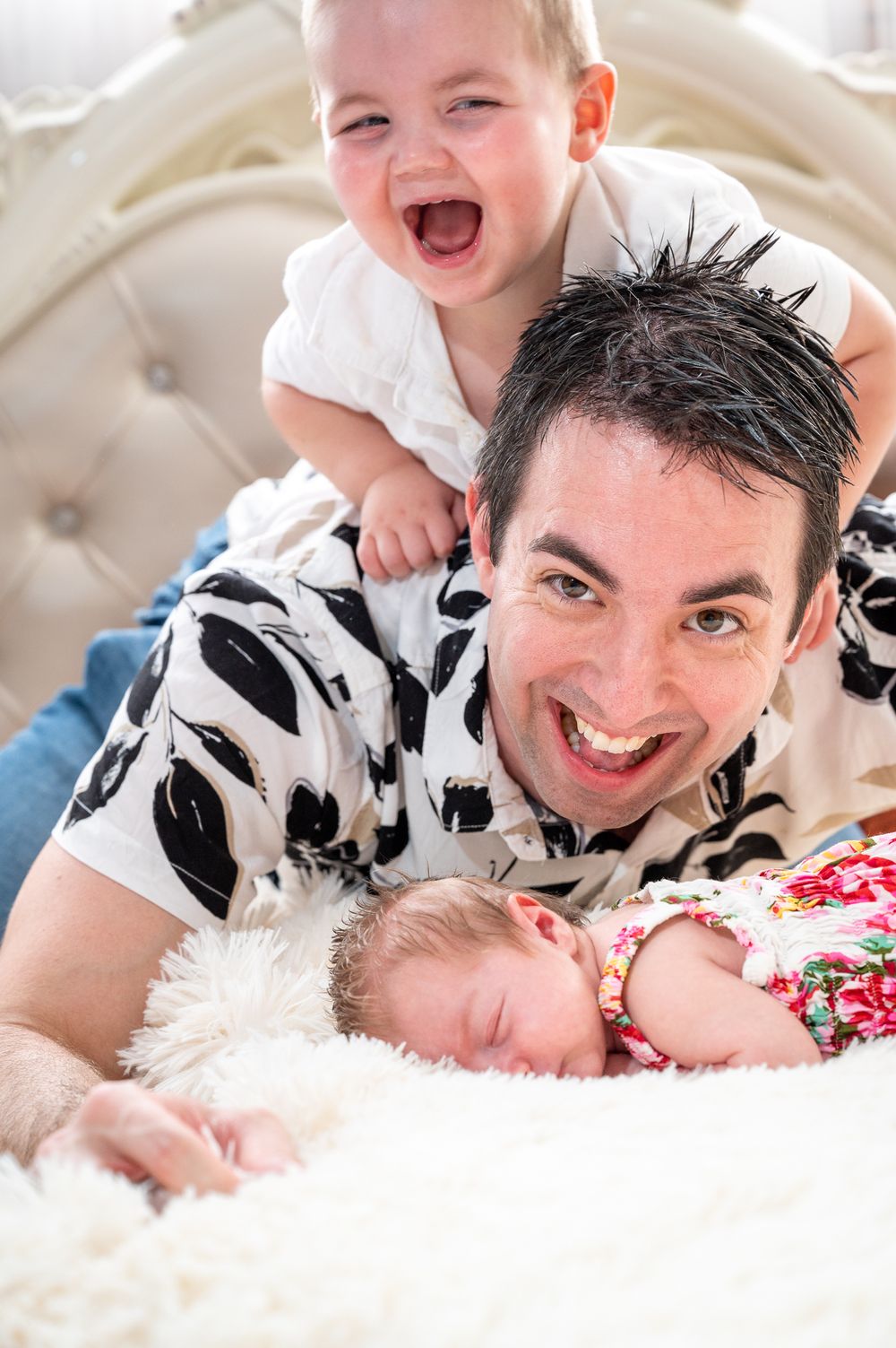 Son playing on Dad while baby sister sleeps underneath