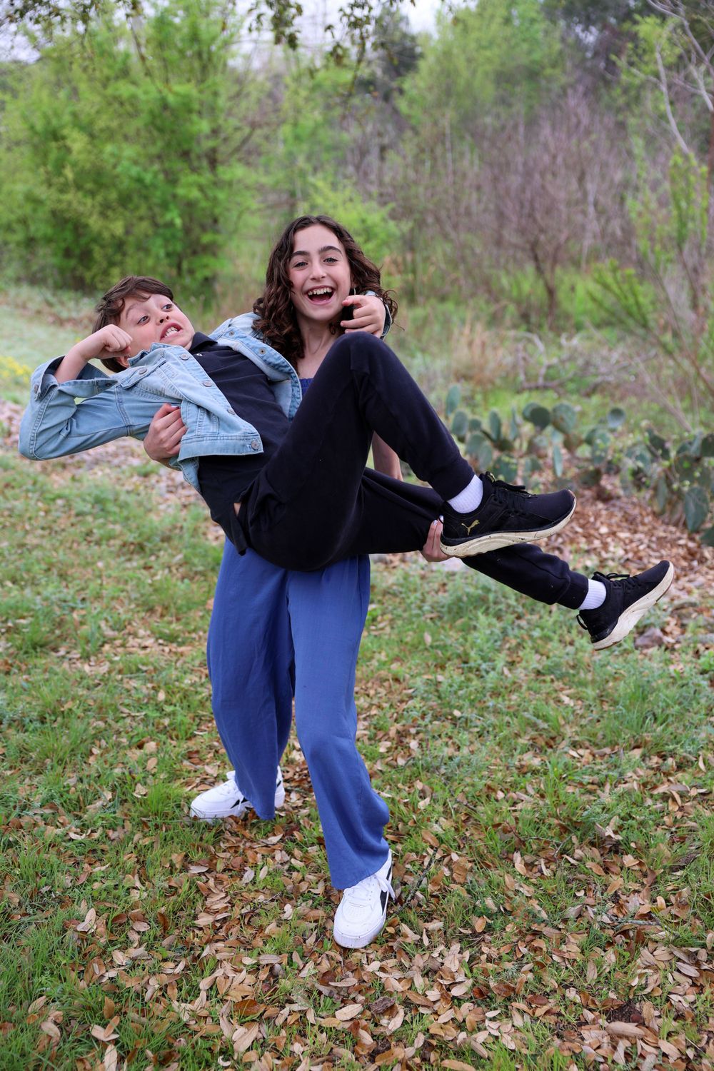 Playful outdoor photo of two people with one carrying the other in fun pose.