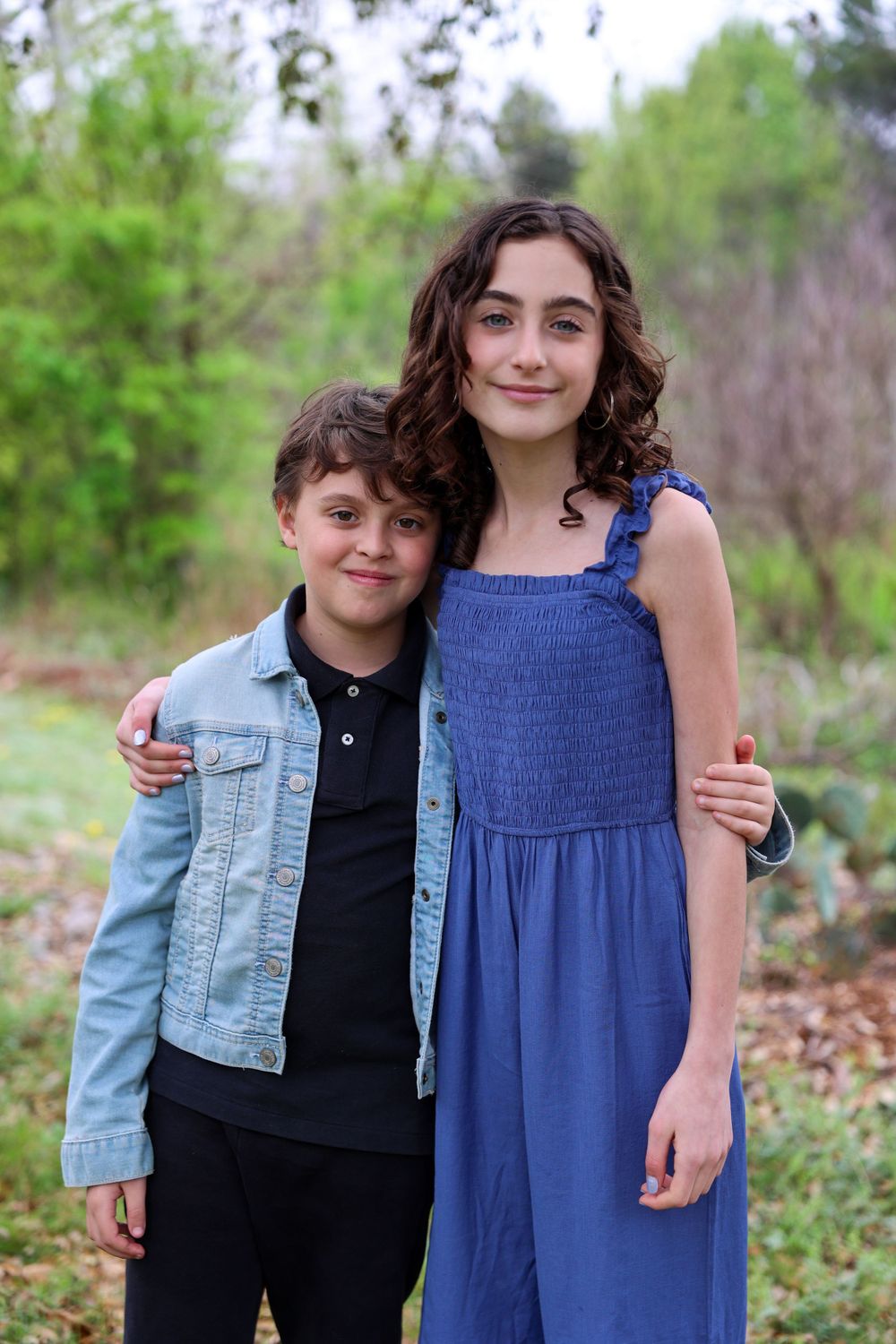 Two young people in casual attire pose together for a portrait in natural outdoor setting.