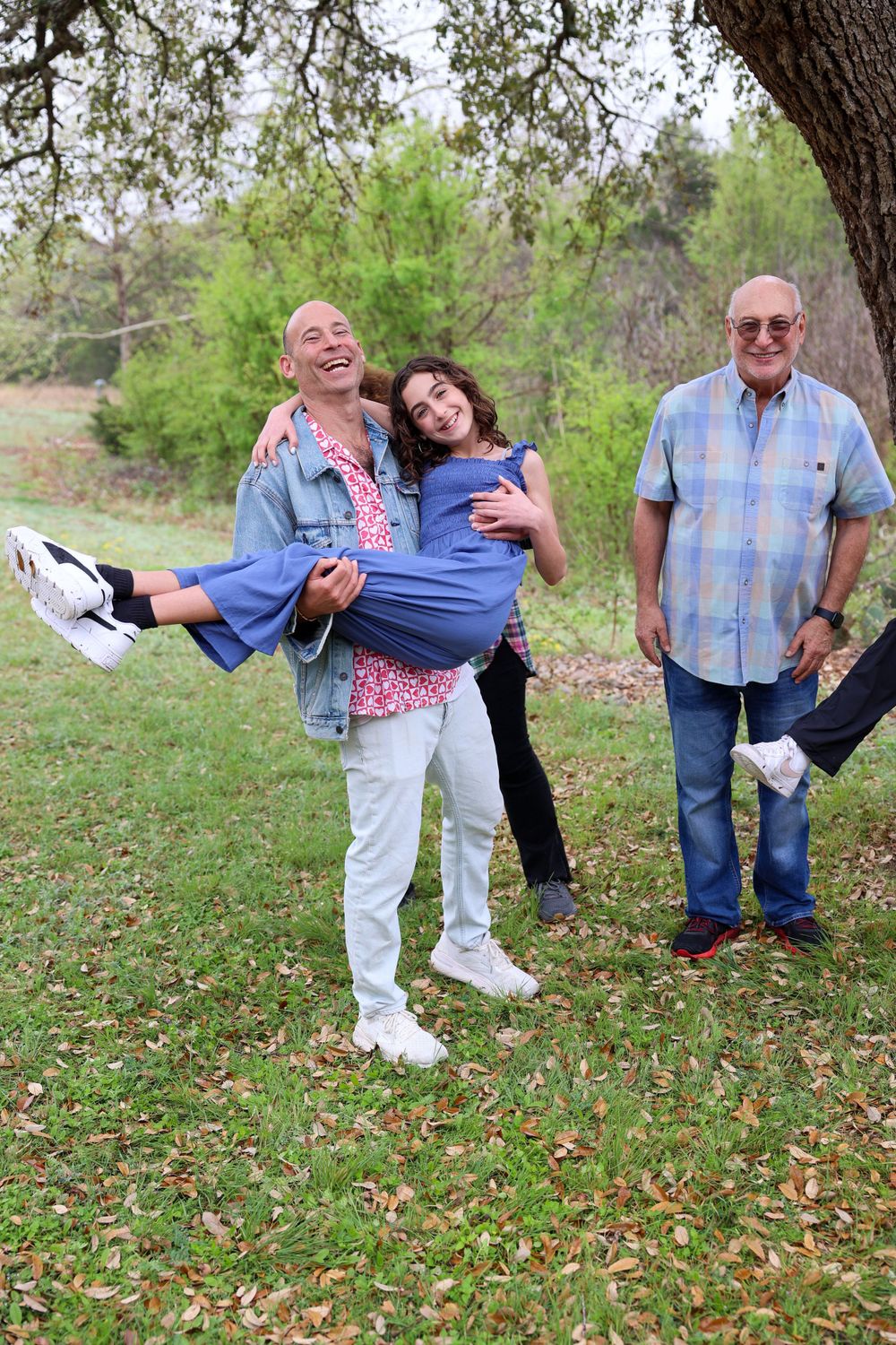 Three people laughing and playing around while posing for a casual outdoor photo.