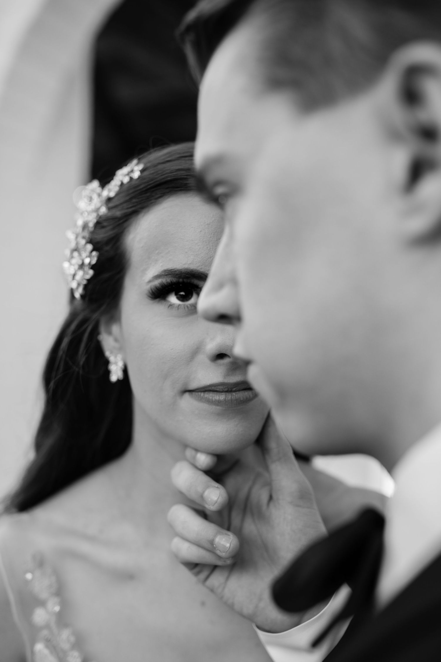 Intimate black and white portrait of elegant wedding couple sharing a tender moment.