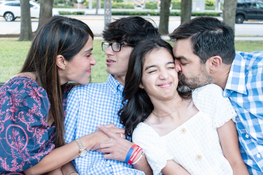 A candid moment shows a family sharing laughter and affection in a park setting.