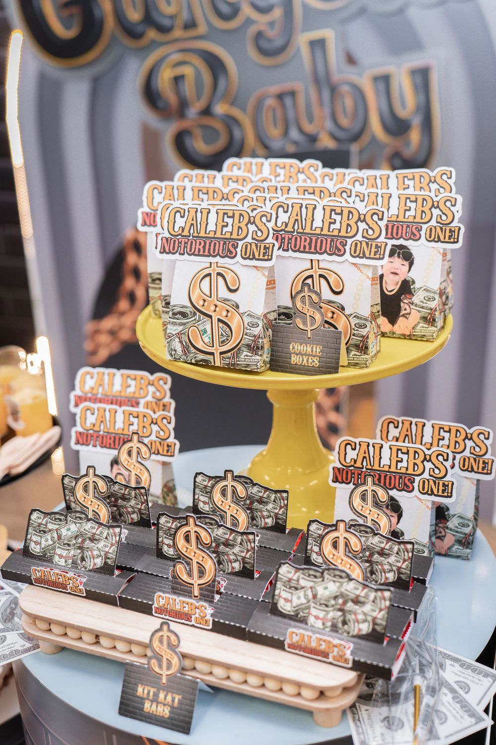Money-themed party decorations displayed on gold cake stand with dollar sign designs.