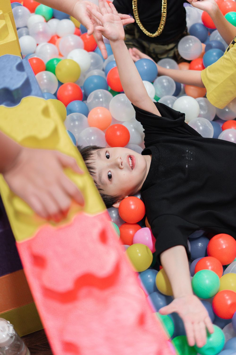 Playful scene in a ball pit filled with multicolored plastic balls.