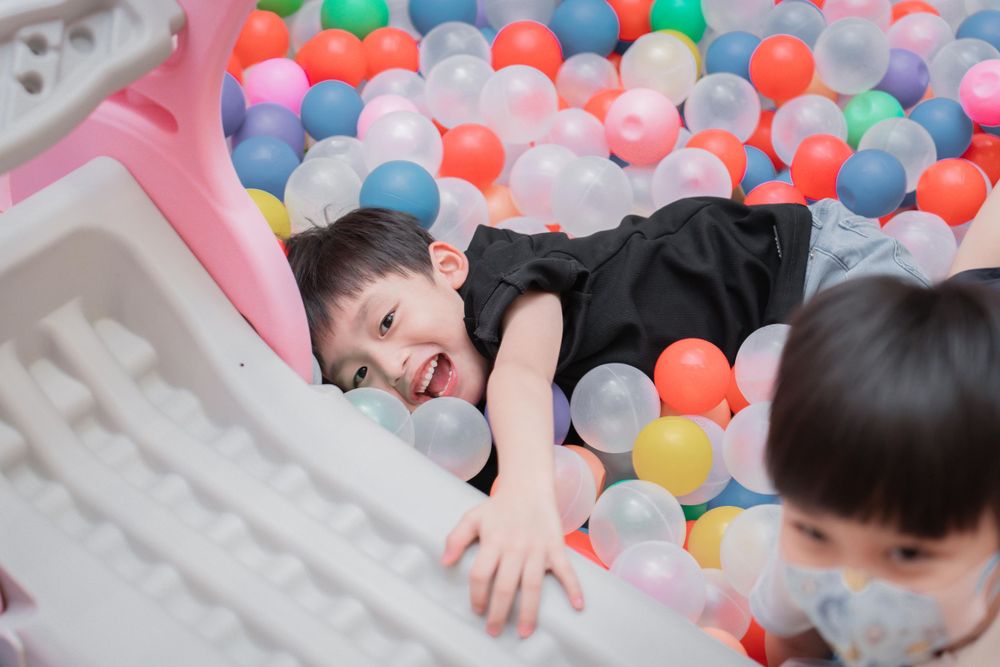 Child playing in a colorful ball pit during a party.
