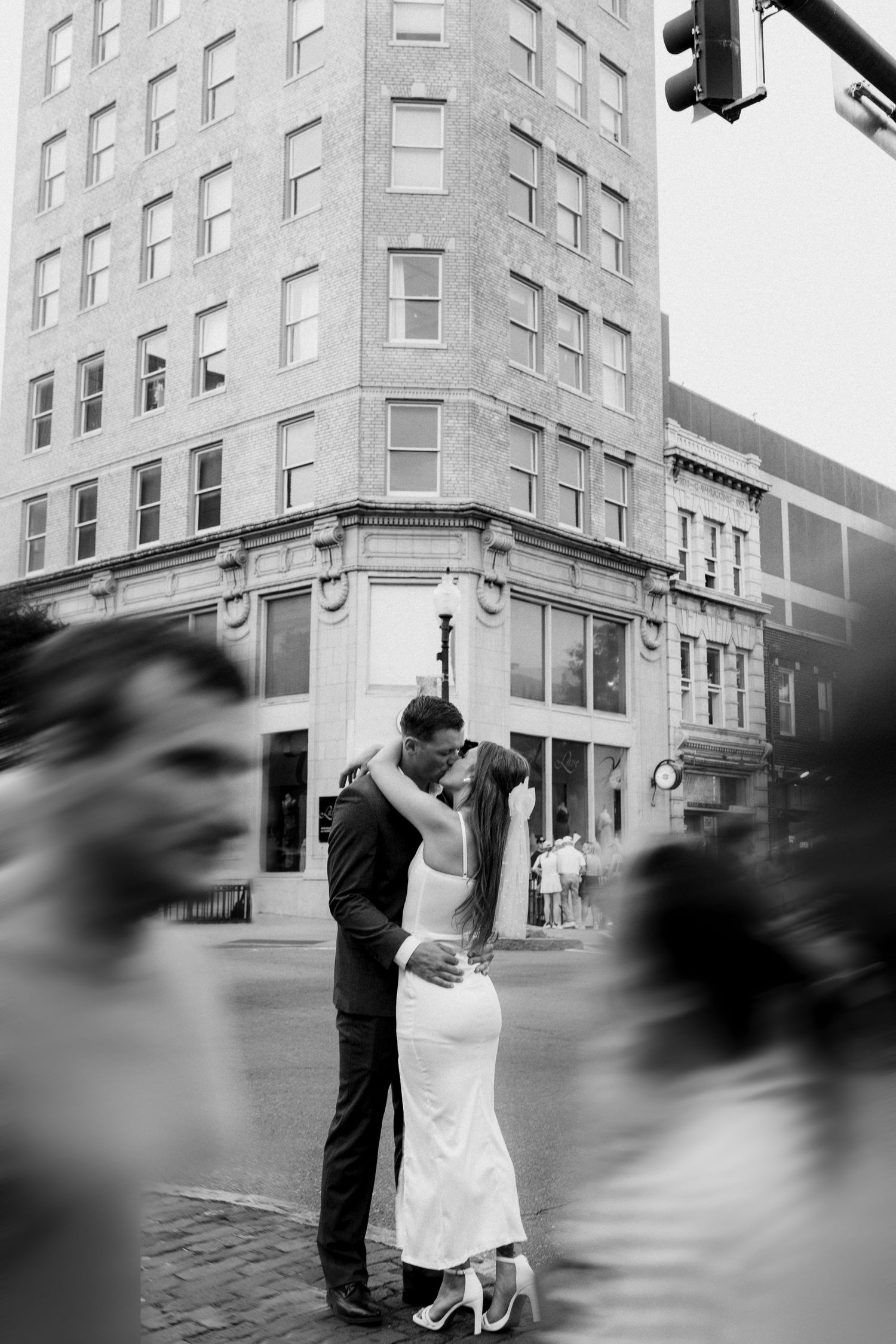 A romantic black and white urban street scene with a couple embracing in front of a historic building.
