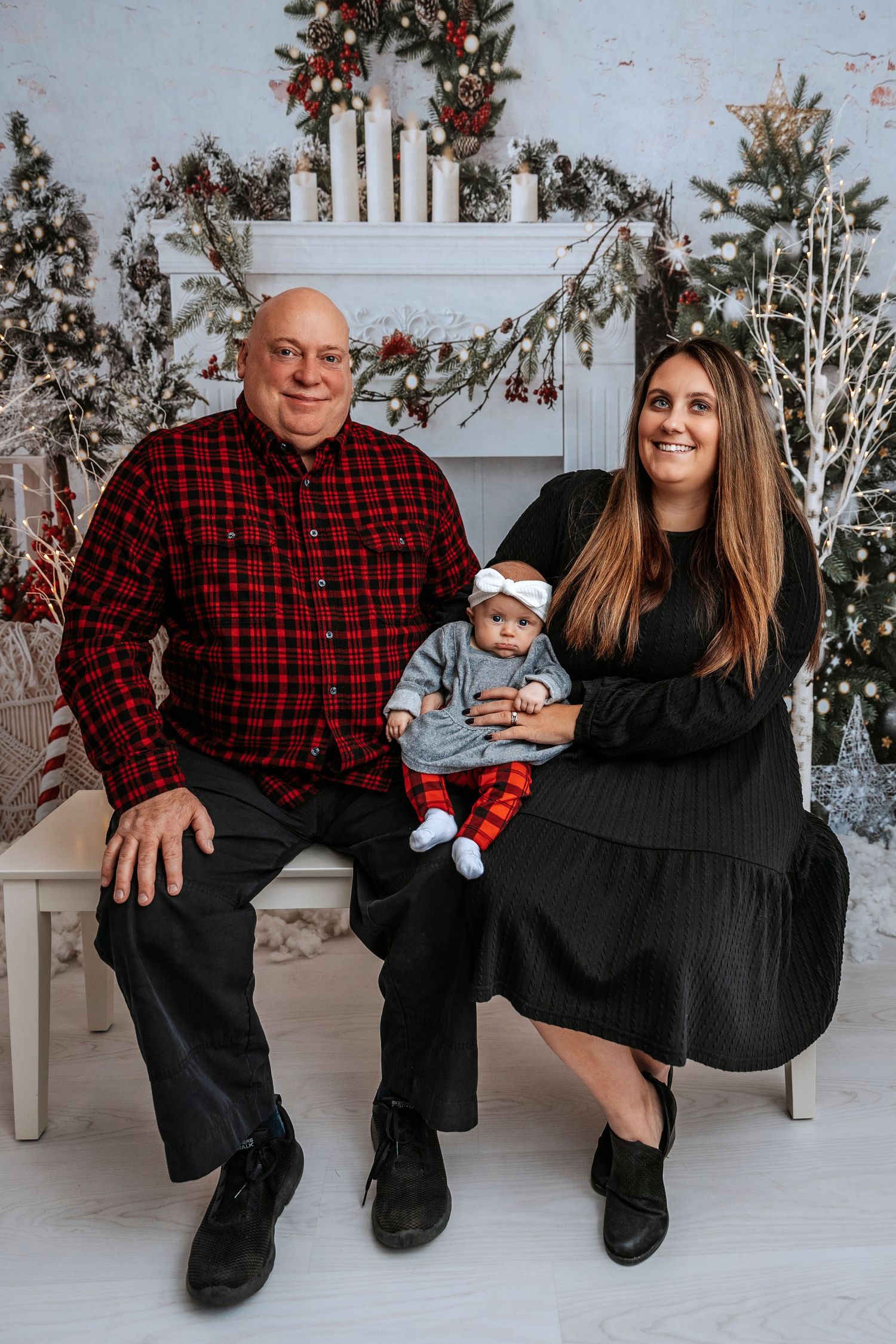 Holiday family portrait with Christmas decorations and white fireplace backdrop.