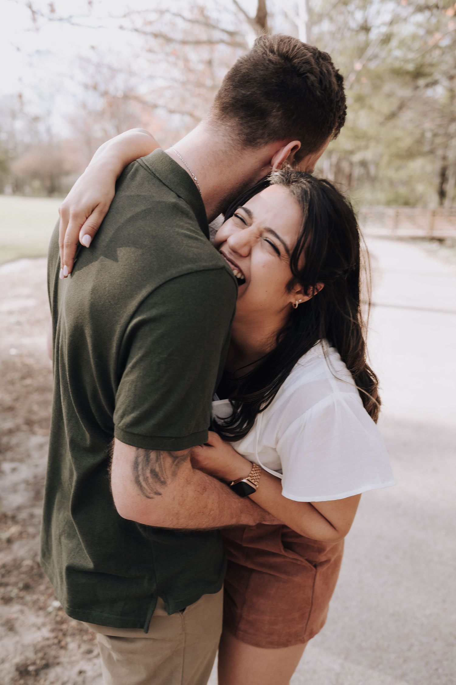 A laughing couple embraces outdoors in a candid moment of joy.