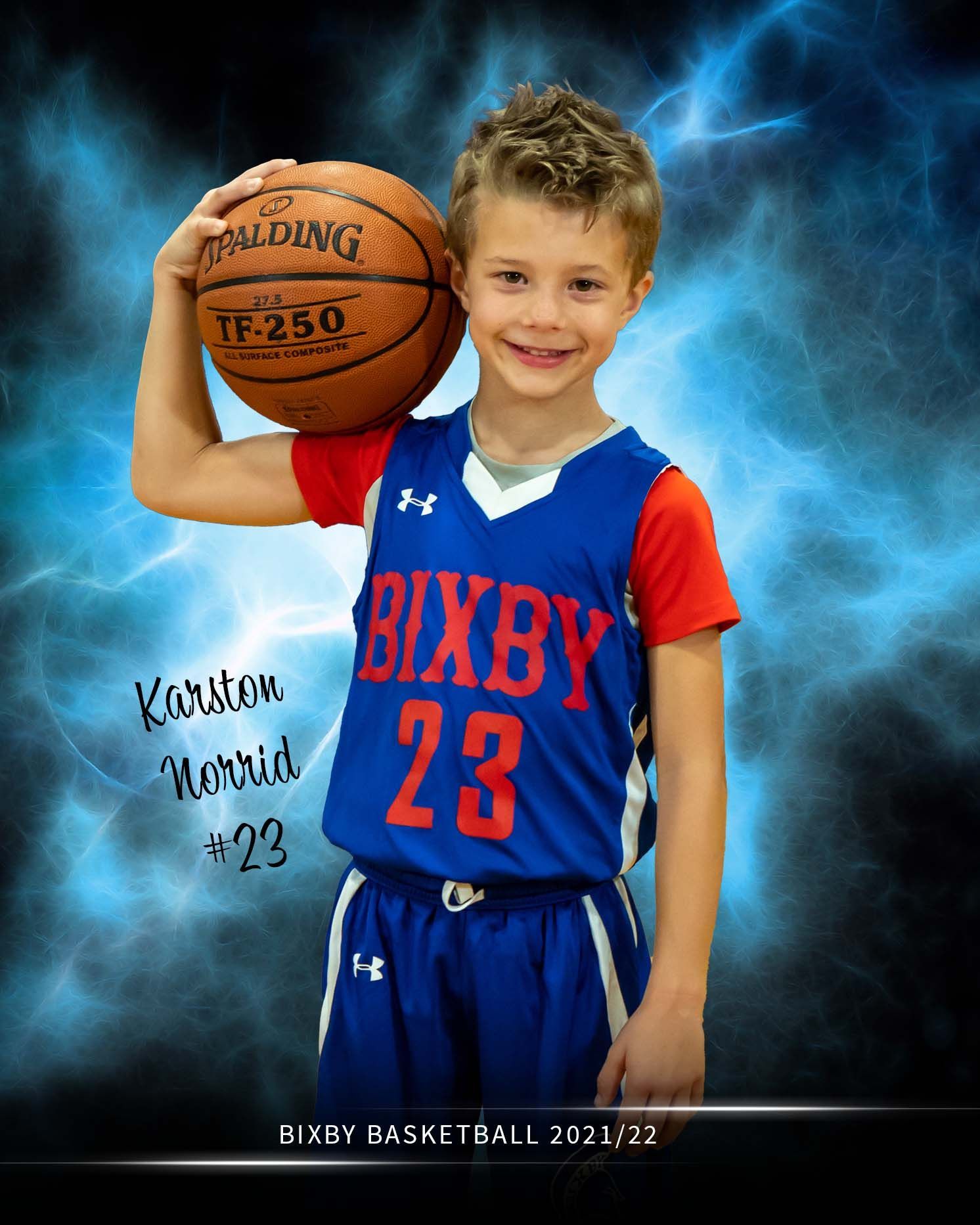 Young boy in Bixby #23 basketball uniform holding Spalding ball for 2021/22 season team photo.