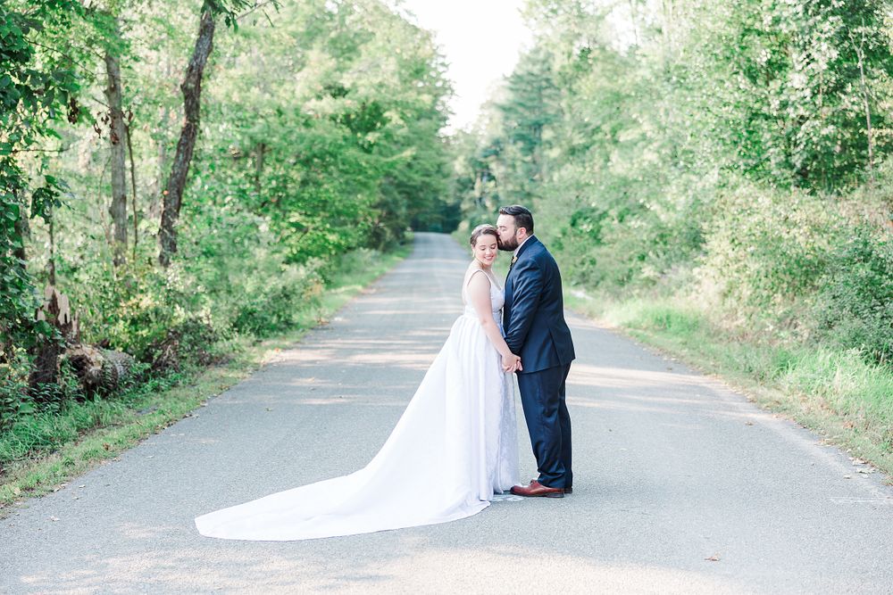 A dreamy wedding portrait on a tree-lined path with sunlight filtering through the foliage.