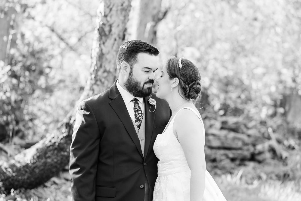 Black and white intimate wedding portrait captured in natural outdoor setting.