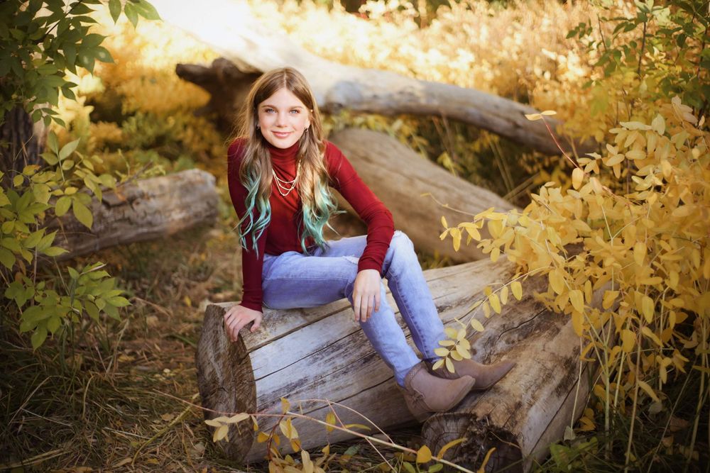 Autumn portrait on fallen log surrounded by golden foliage.
