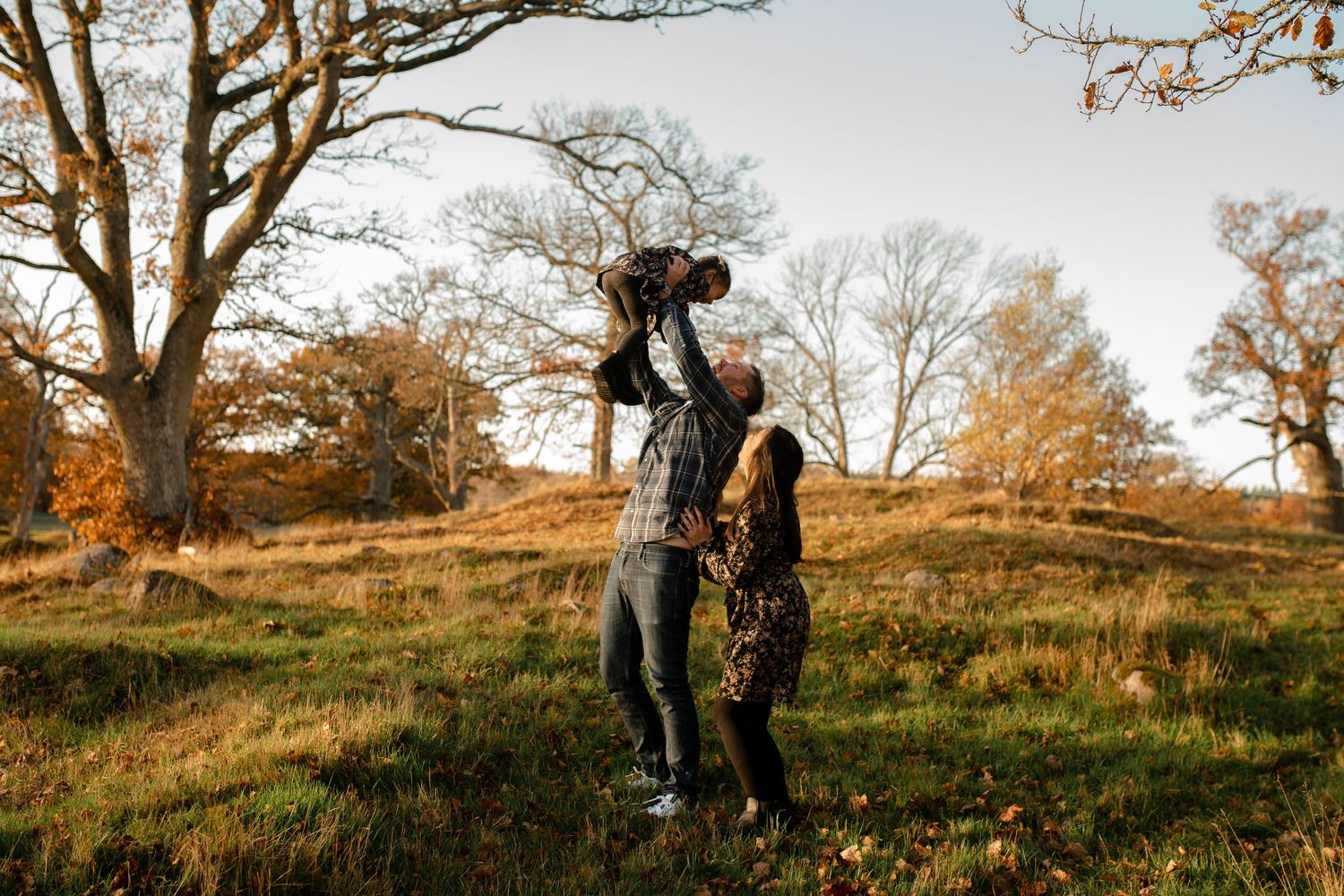 A couple shares a romantic moment on a grassy hilltop during golden hour in autumn.