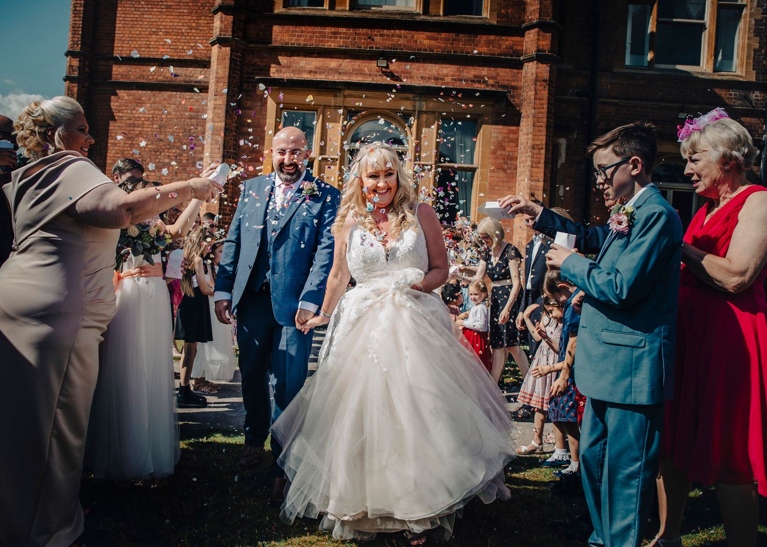 emotive candid wedding photography as the couple walk through an avenue of confetti