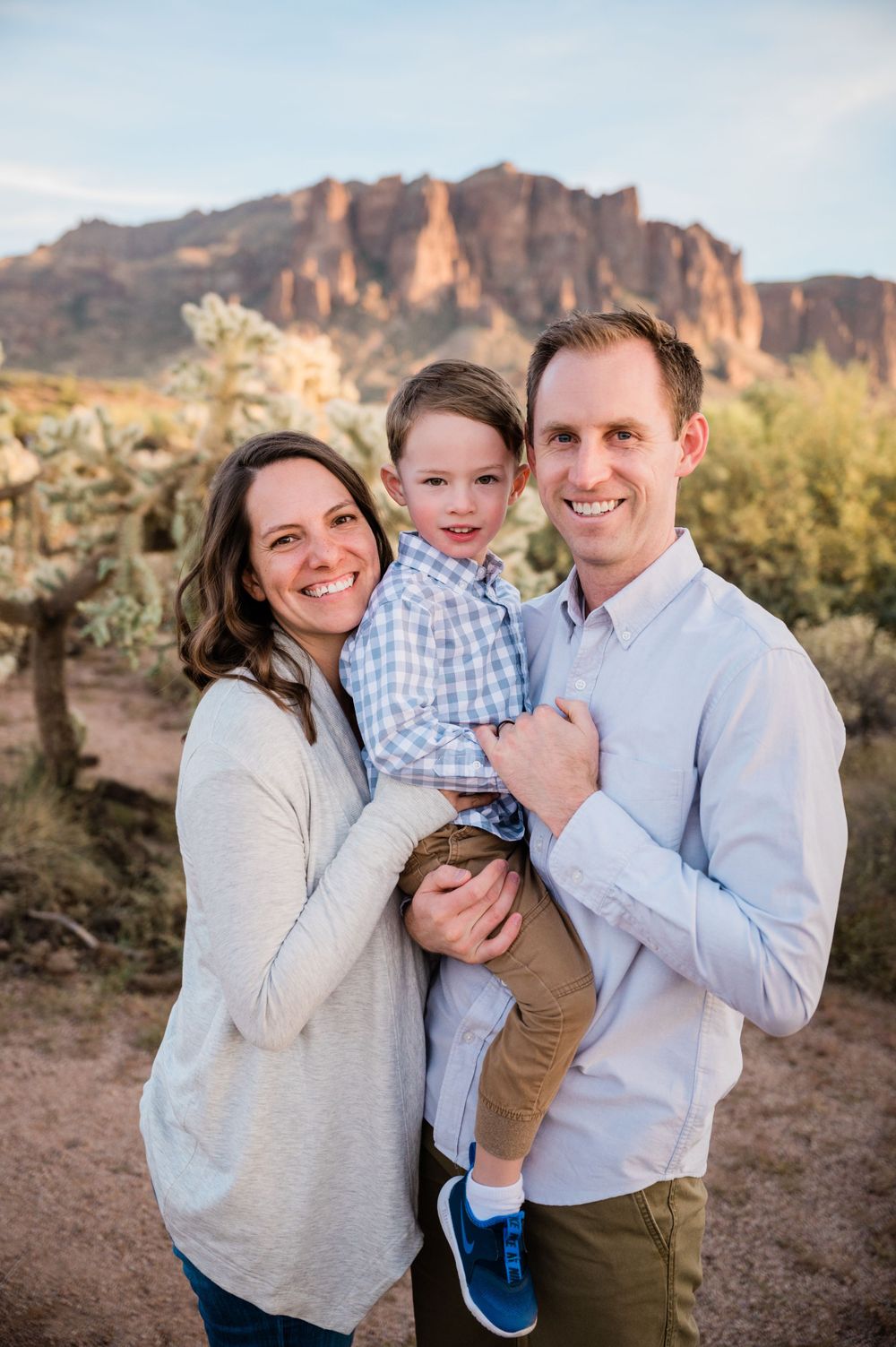 A family poses together against a desert mountain backdrop at sunset.