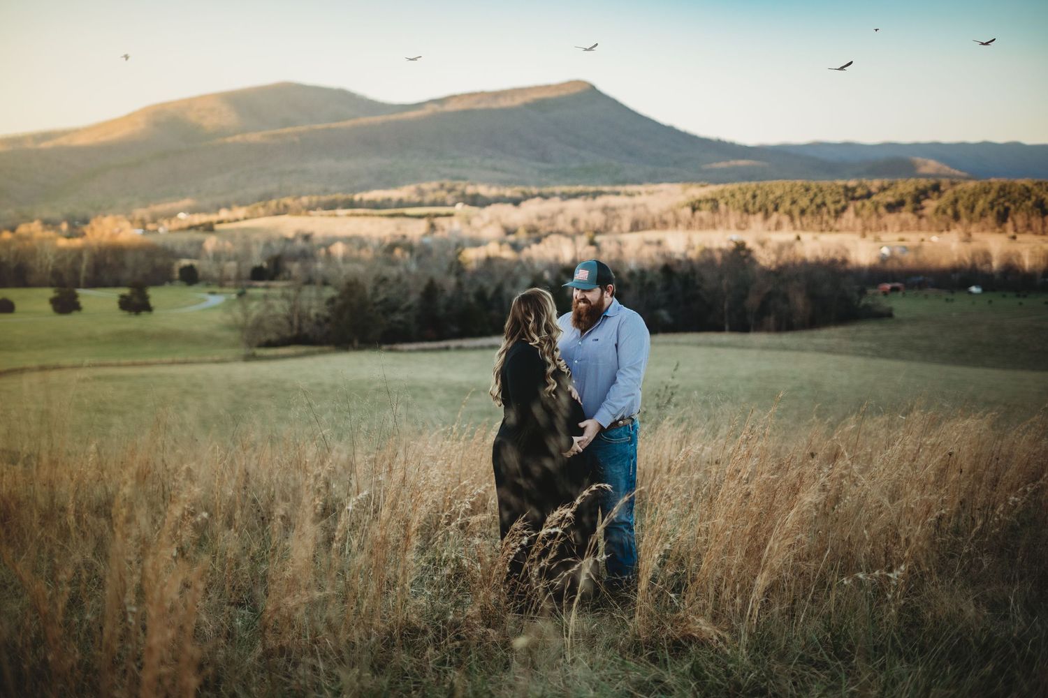 Rolling meadows with mountain views and tall grass swaying in golden afternoon light.