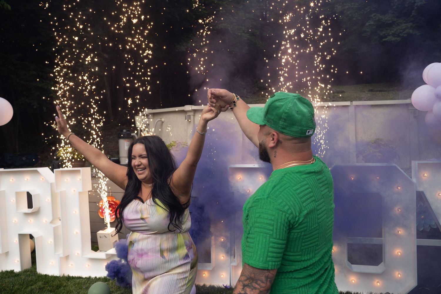 Golden sparklers illuminate the night sky at a gender reveal celebration.