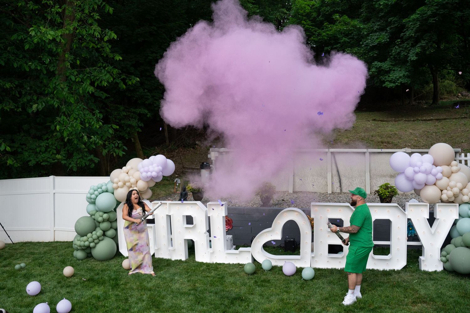 Pink smoke fills the air during an outdoor gender reveal celebration.