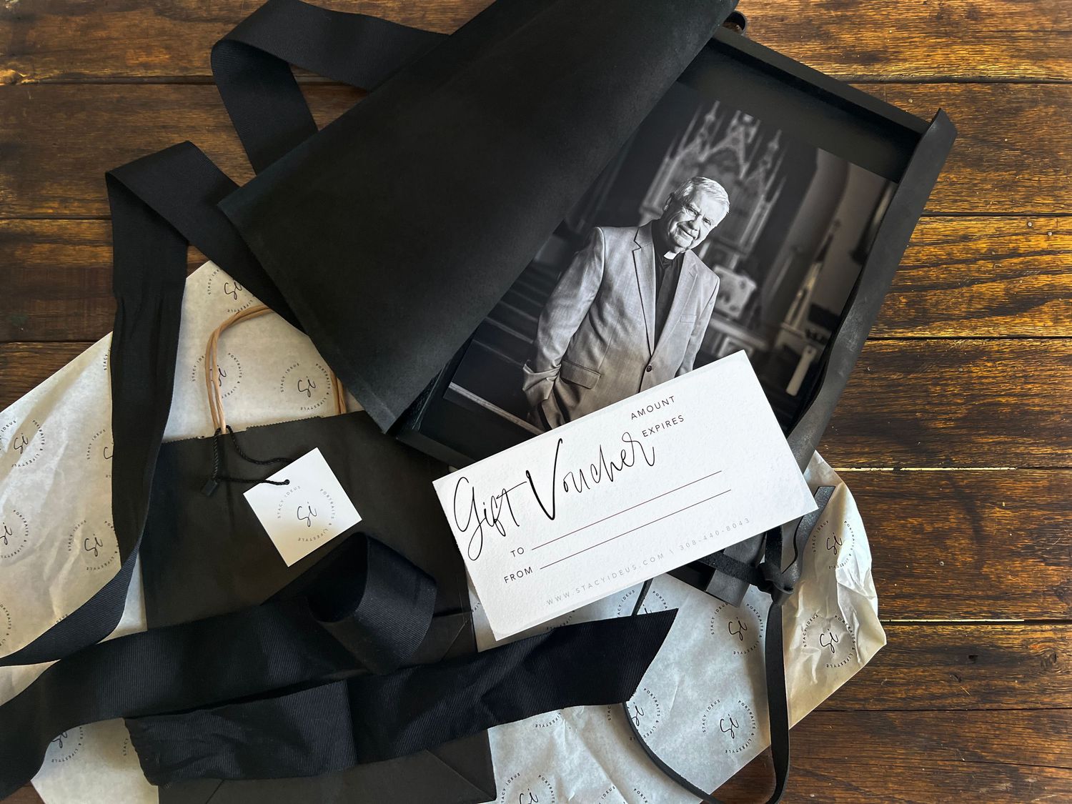 A vintage photograph and business card displayed on a rustic wooden surface.