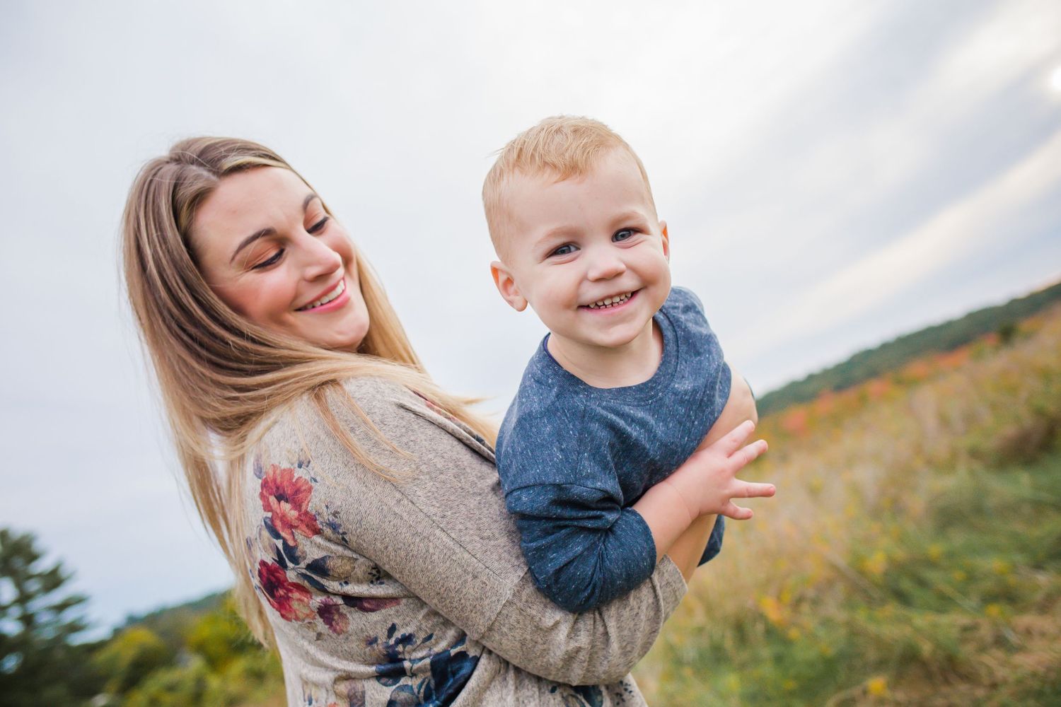 A playful outdoor portrait captured in natural lighting with autumn scenery in the background.