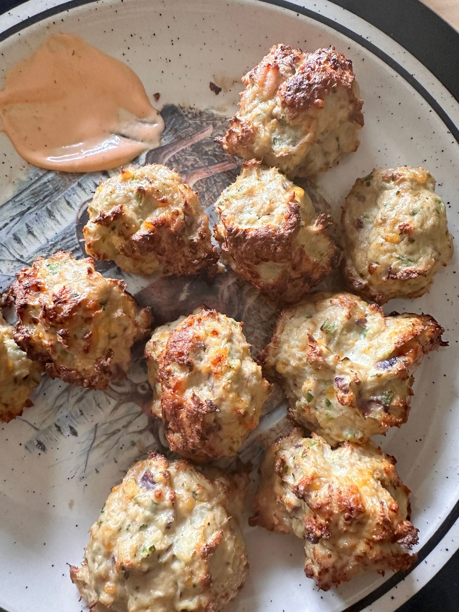 Golden brown meatballs arranged on a plate with creamy sauce.