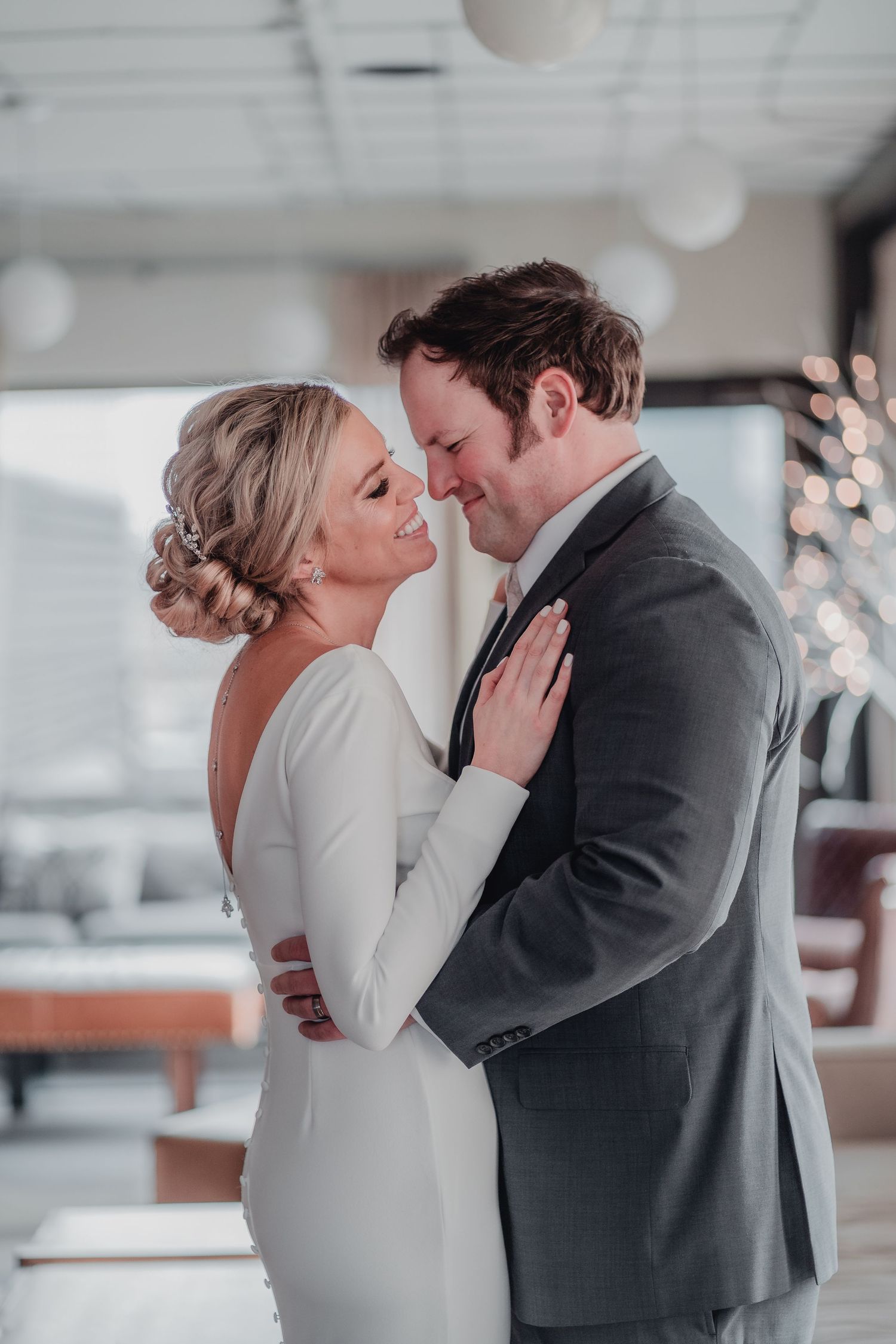 Intimate indoor wedding moment captured in soft lighting with elegant formal attire.